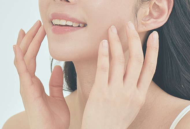 양손을 턱선에 대고 웃는 여성의 입과 턱 클로즈업